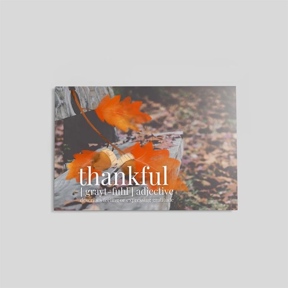 thankful text with orange leaves on wood background